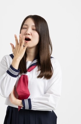 あくびをする制服姿の女子学生（イメージ）
